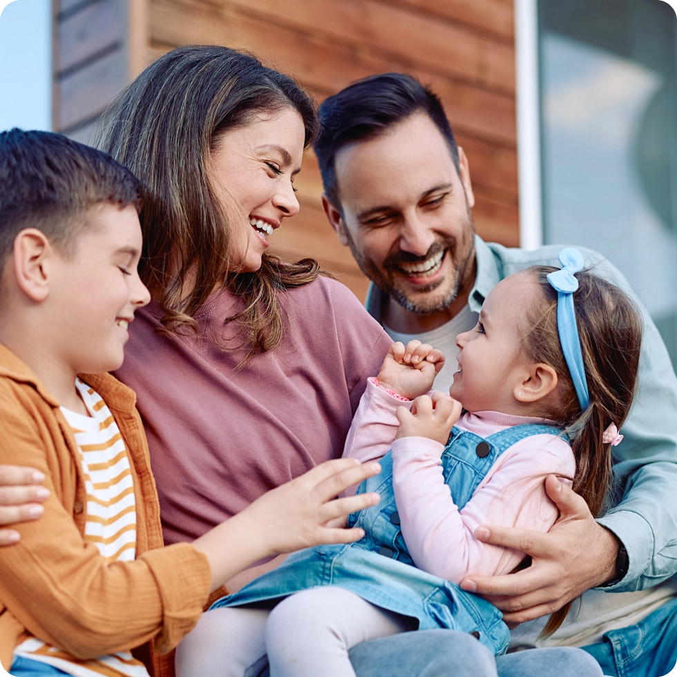 Happy family of four sitting together outdoors smiling